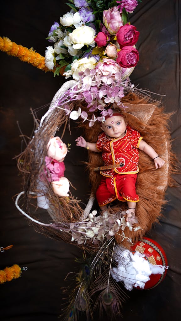 Cute baby dressed in vibrant Indian attire nestled in a floral wreath. Perfect for cultural celebration themes.