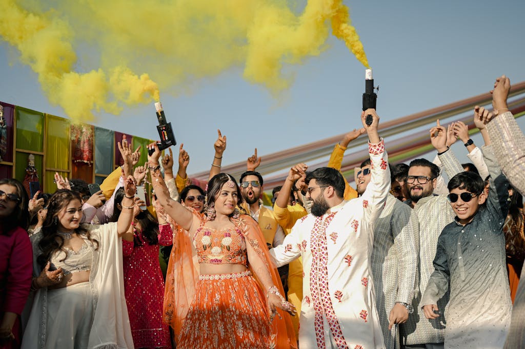 Joyful group celebrating Indian wedding with colorful smoke bombs.