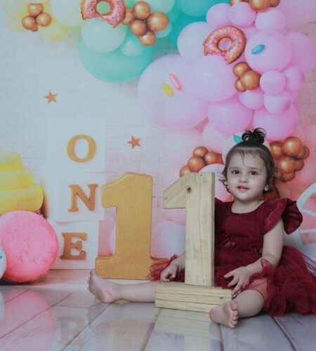 Charming first birthday photoshoot with a toddler girl in a vibrant, colorful setting.