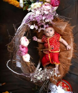 Cute baby dressed in vibrant Indian attire nestled in a floral wreath. Perfect for cultural celebration themes.