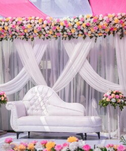 Luxurious wedding stage setup decorated with vibrant floral arrangements and a white sofa, perfect for celebrations.