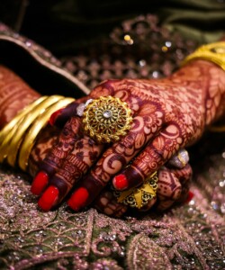 Close-up of beautifully hennaed hands with ornate jewelry, showcasing traditional culture in South India.