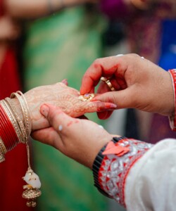 Close-up of couple exchanging rings in a vibrant traditional Indian wedding ceremony.
