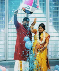 Happy couple at a vibrant gender reveal party indoors with blue confetti.