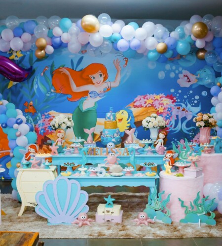 A colorful Little Mermaid themed birthday party with balloons and dessert table indoors.