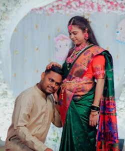 A joyful couple celebrating a traditional Indian baby shower with vibrant attire and decorations.