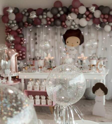 A magical indoor birthday party setup featuring balloons, fairy lights, and themed decorations.