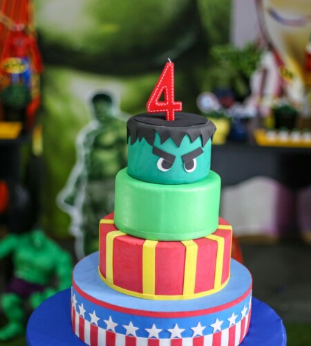 Vibrant superhero-themed birthday cake with a number four candle, perfect for kids' celebrations.